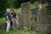 Zwei Frauen betrachten einen alten Grabstein auf dem Alten Friedhof