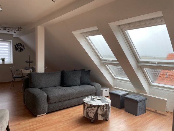 Zimmer im Dachgeschoss mit Sofa und Tisch.