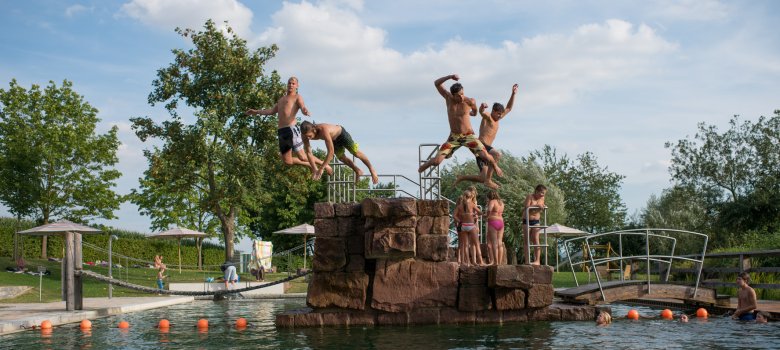Junge Menschen springen den Sprungtum im Naturbad runter