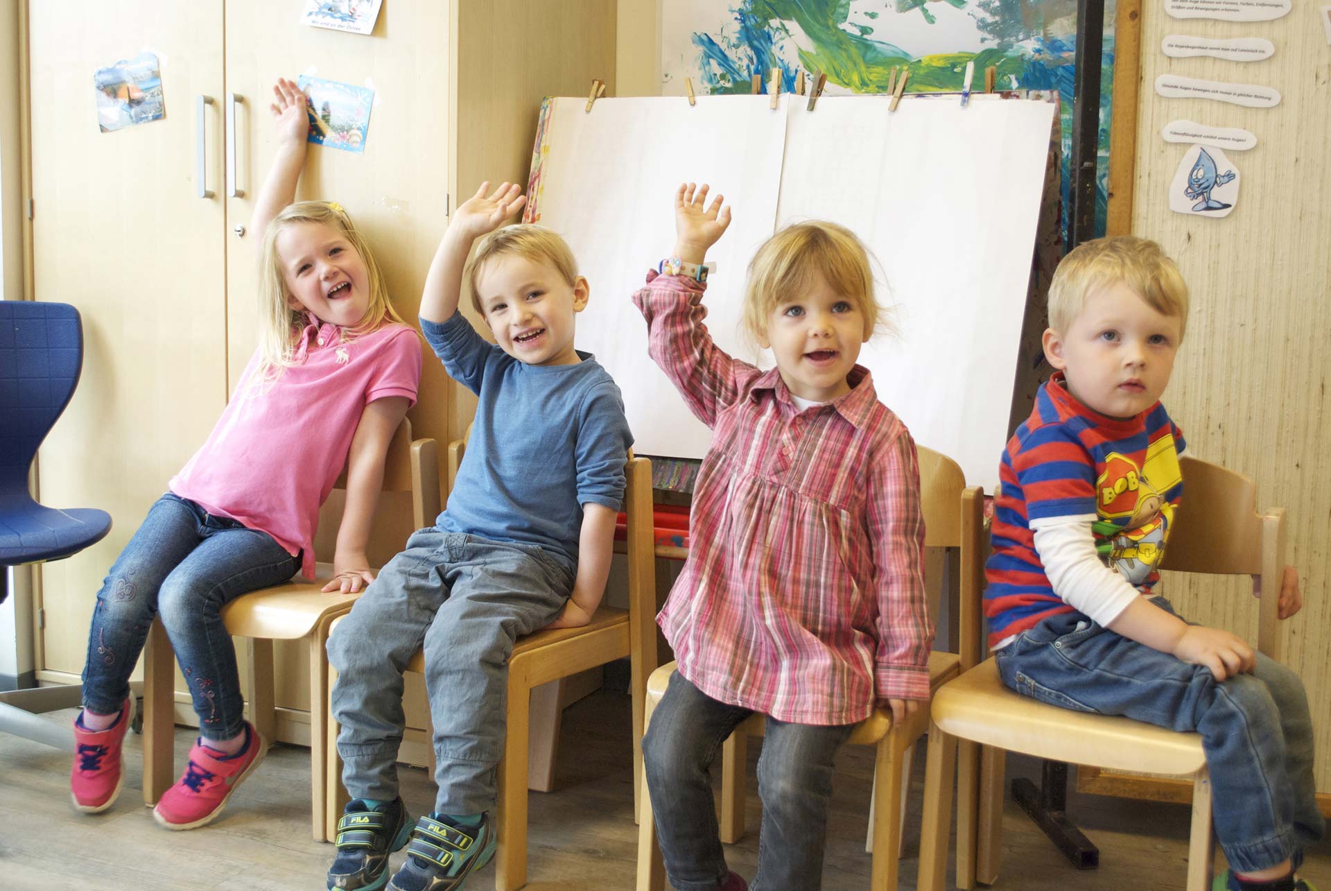 Sitzende Kinder heben die Hände