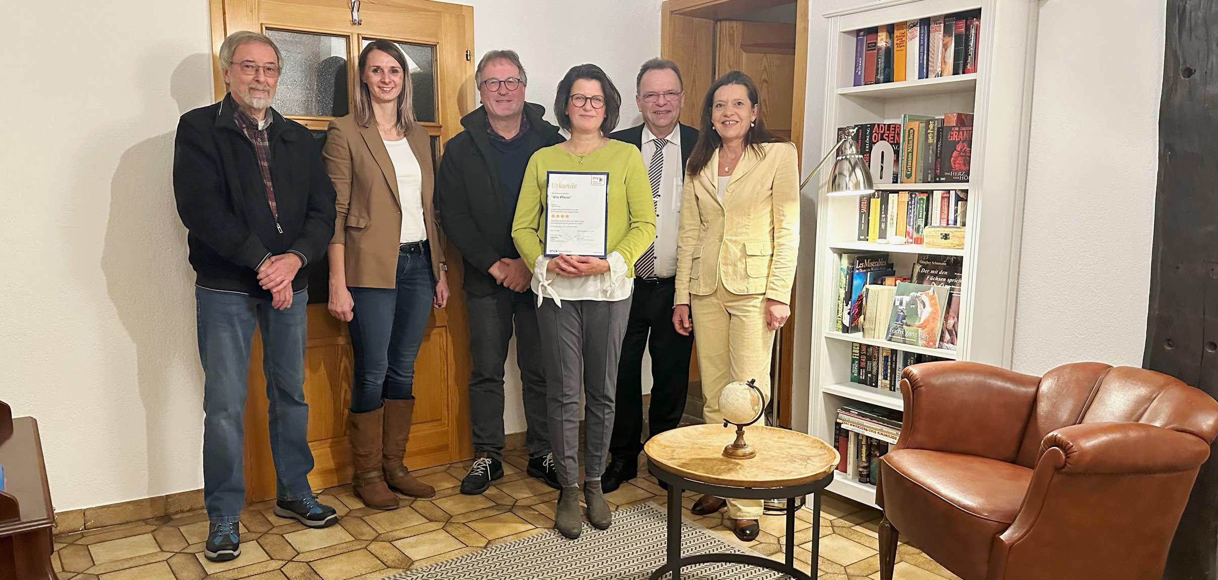 Sechs Personen mit Urkunde im Flur der Ferienwohnung