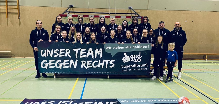 Gruppenbild einer Damenfußballmannschaft mit einem Banner mit der Aufschrift UNSER TEAM GEGEN RECHTS.