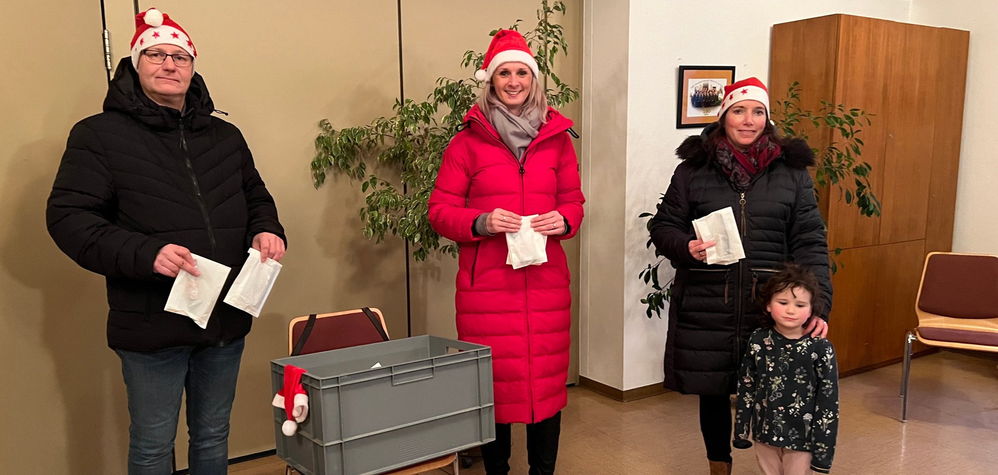 Drei Erwachsene und ein Kind mit Kiste im Dorfgemeinschaftshaus