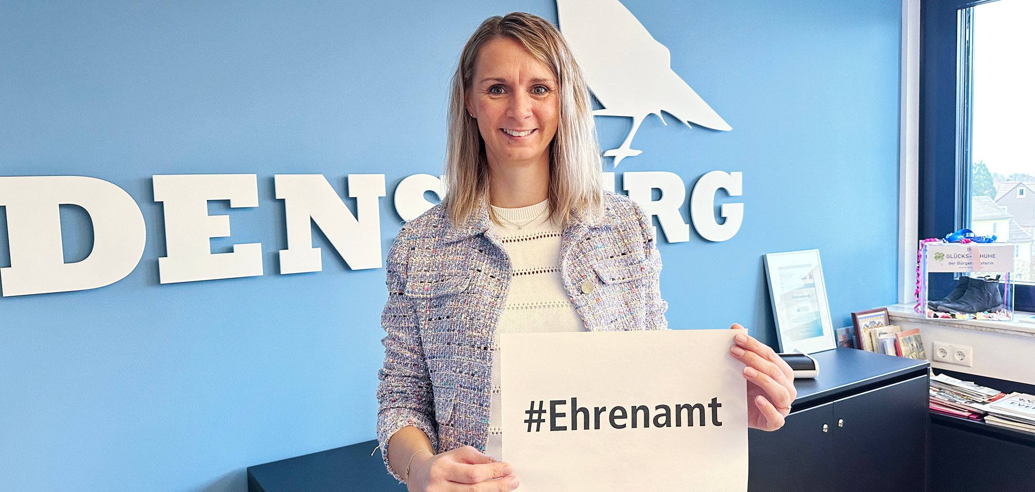 Bürgermeisterin mit Schild #Ehrenamt in der Hand