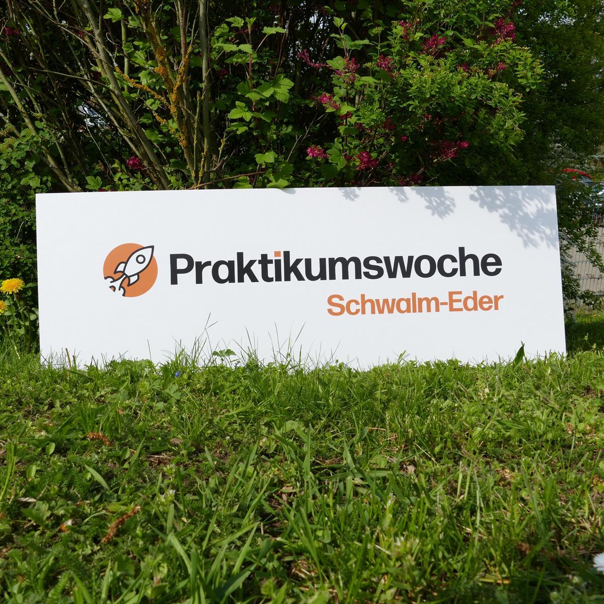 Plakat mit Aufschrift Praktikumswoche Schwalm-Eder auf grüner Wiese. 