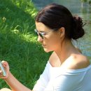 Junge Frau ist dabei zu sehen, wie sie in ihrem Smartphone etwas liest.
