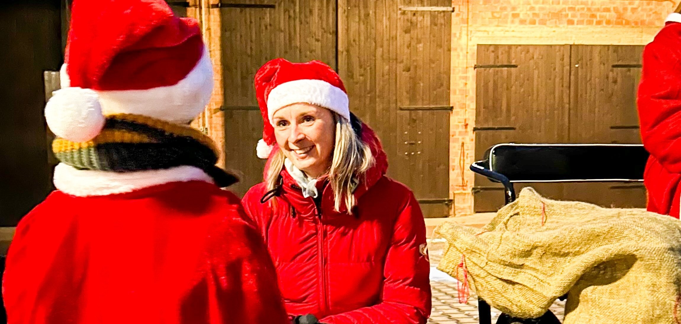 Bürgermeisterin Sina Massow mit Nikolausmütze und roter Jacke vor einem Kind mit roter Jacke und Nikolausmütze