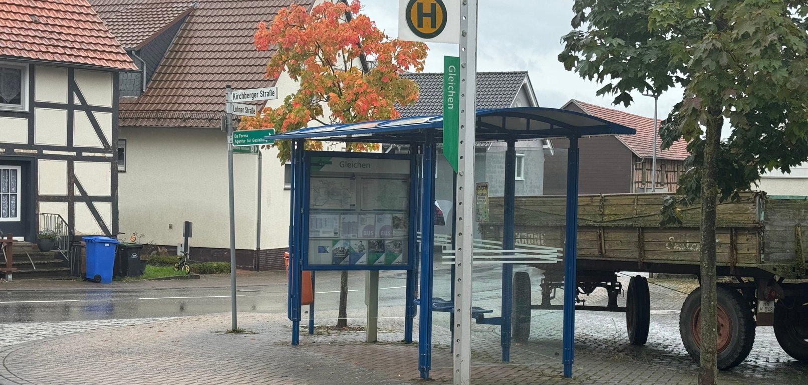 Bushaltestelle in Gleichen mit Unterstand und Haltestellenschild und Traktoranhänger dahinter