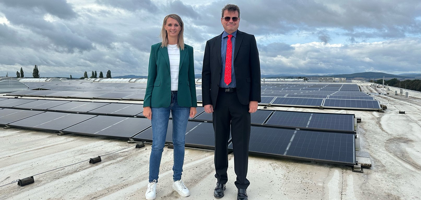 Herr Rudolph und Frau Massow vor der Photovoltaikanlage auf dem Dach der Hallen
