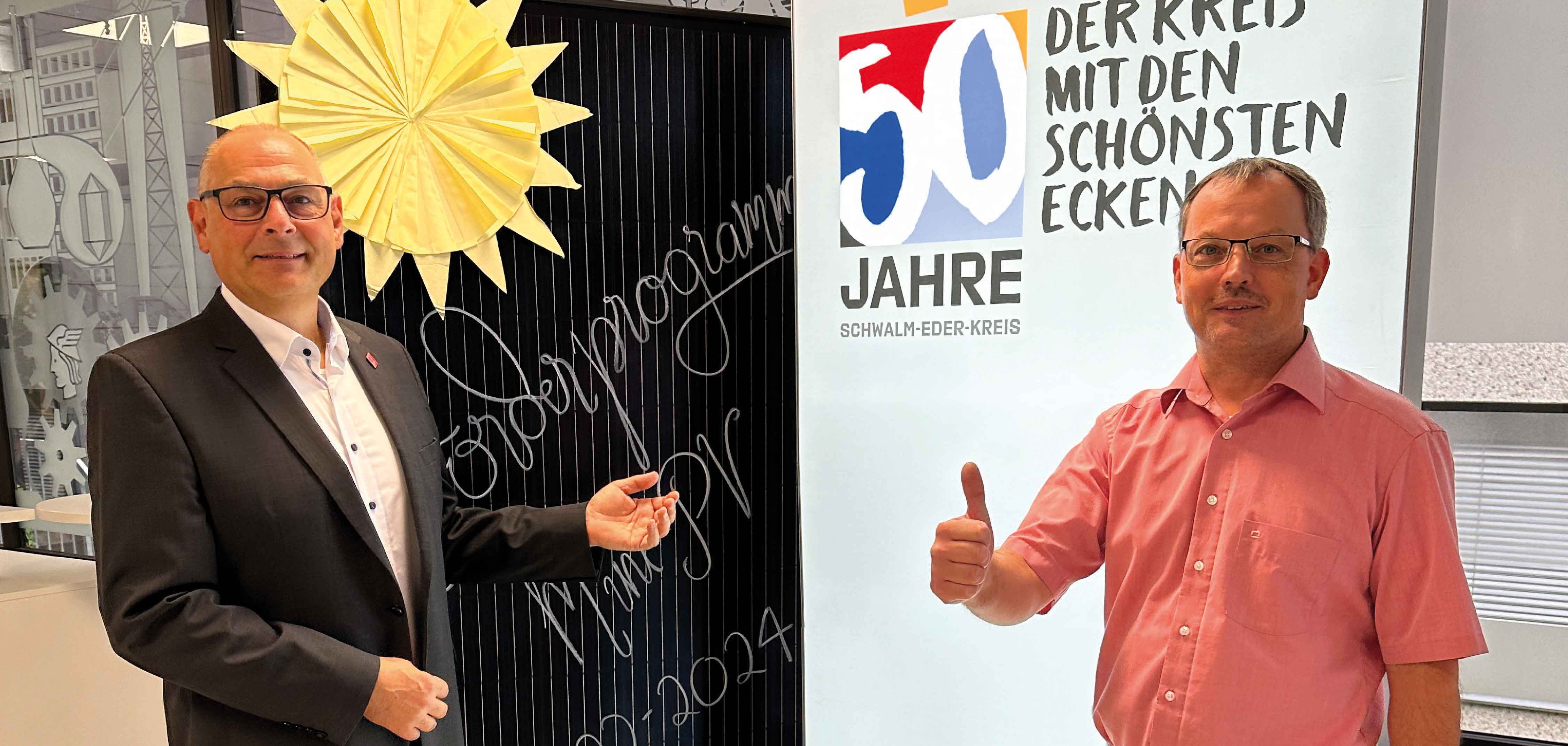 Zwei stehende Männer präsentieren ein Balkonkraftwerk. 