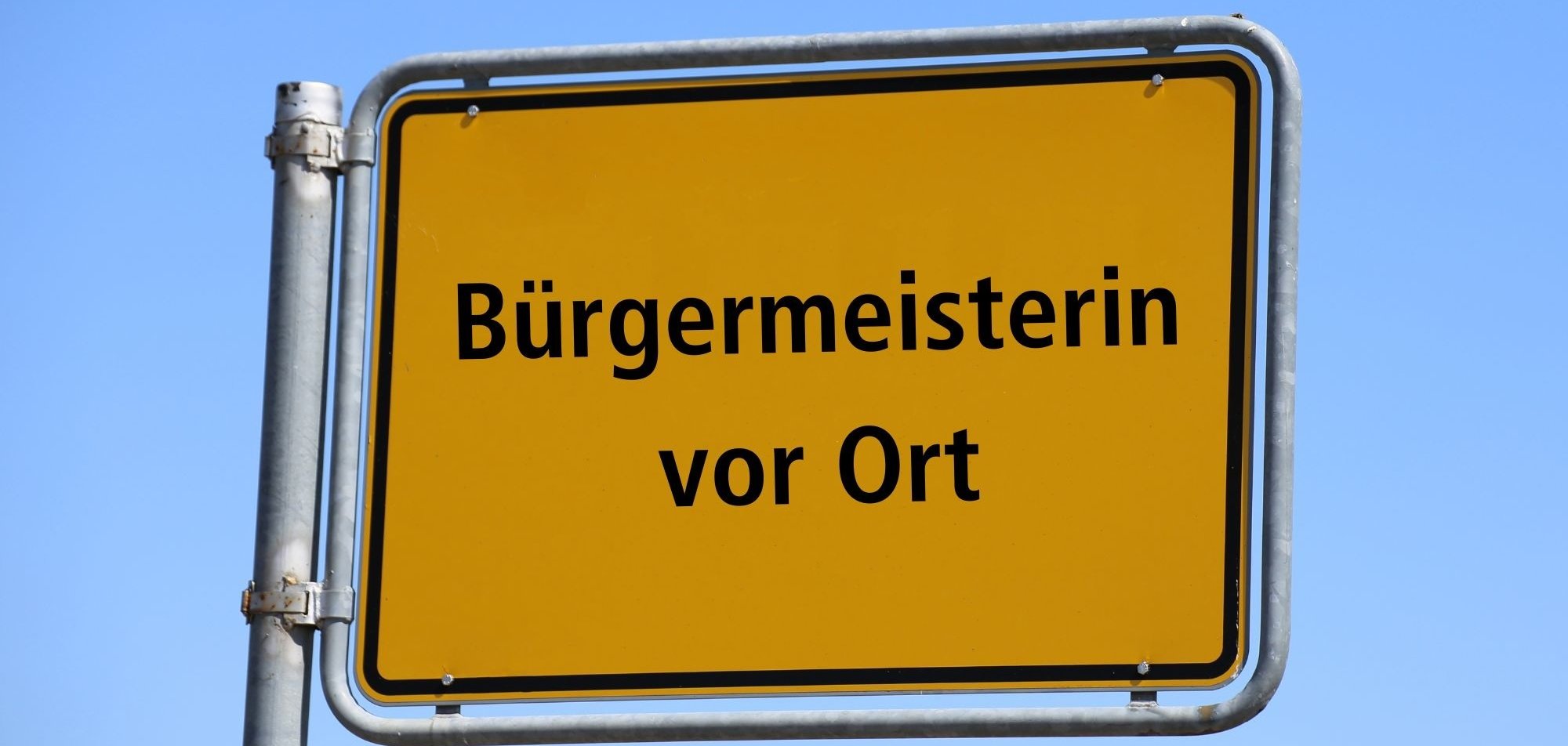 Ortsschild mit Bürgermeisterin vor Ort