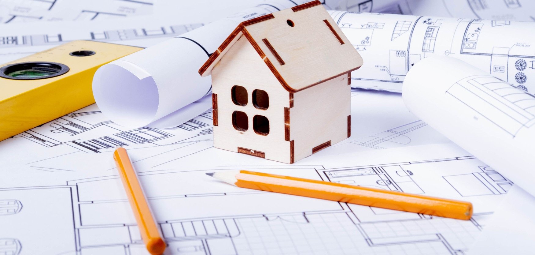 Minihaus auf einem Plan mit Wasserwaage und Stiften