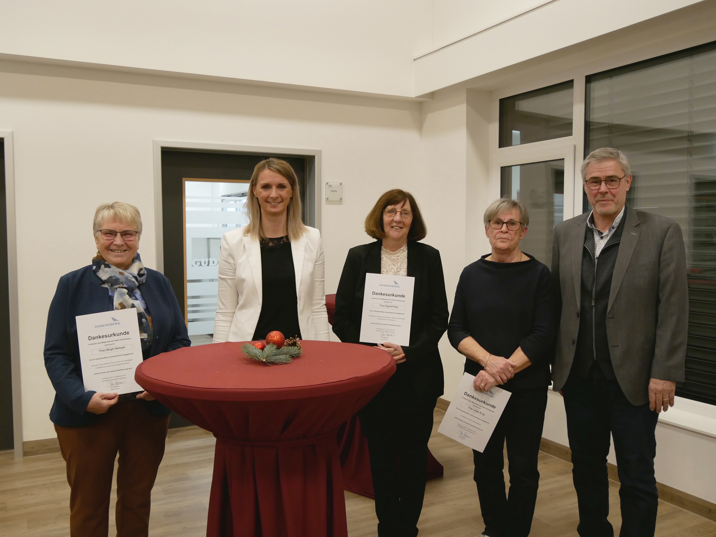 vier Frauen und ein Mann mit Urkunden in der Hand an einem Tisch stehend