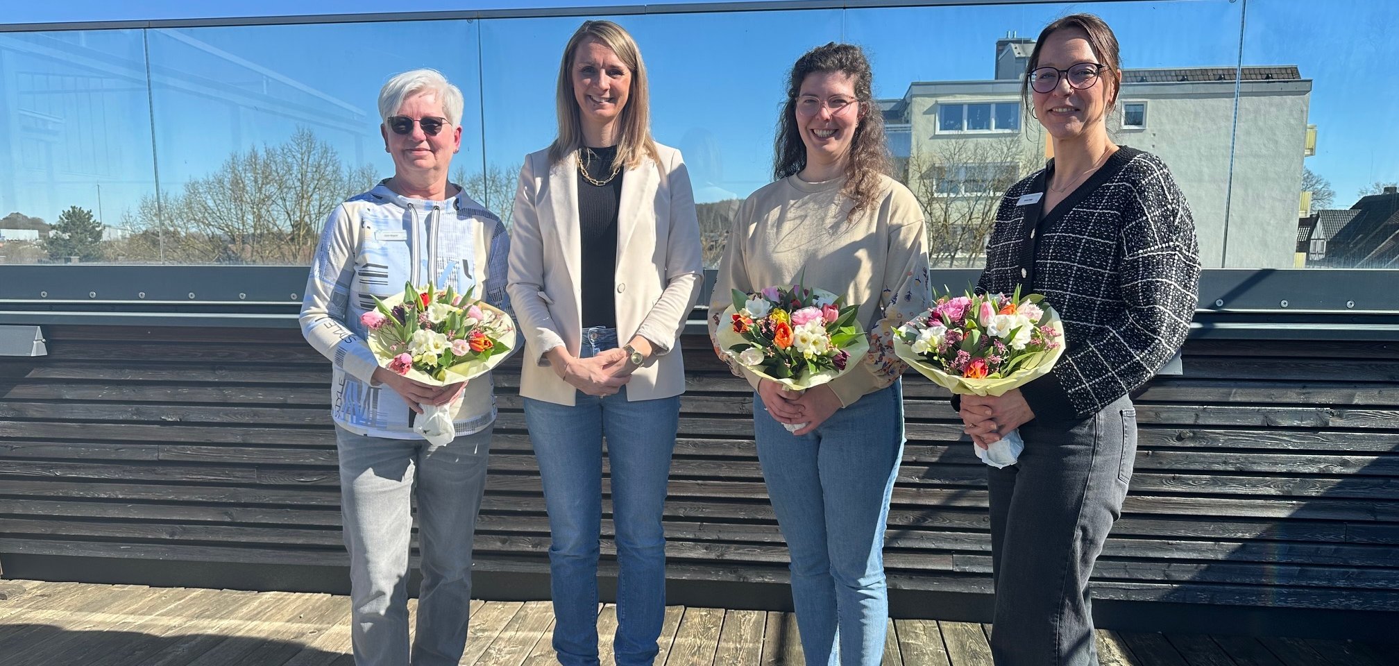 Vier Frauen, drei mit Blumensträußen, auf der Dachterasse des Rathauses
