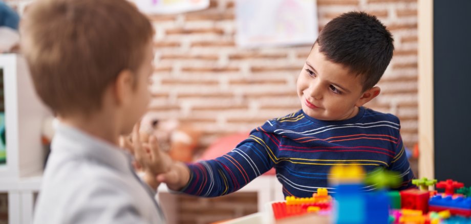 Two kids playing with construction blocks sitting on table at kindergarten Two kids playing with construction blocks sitting on table at kindergarten